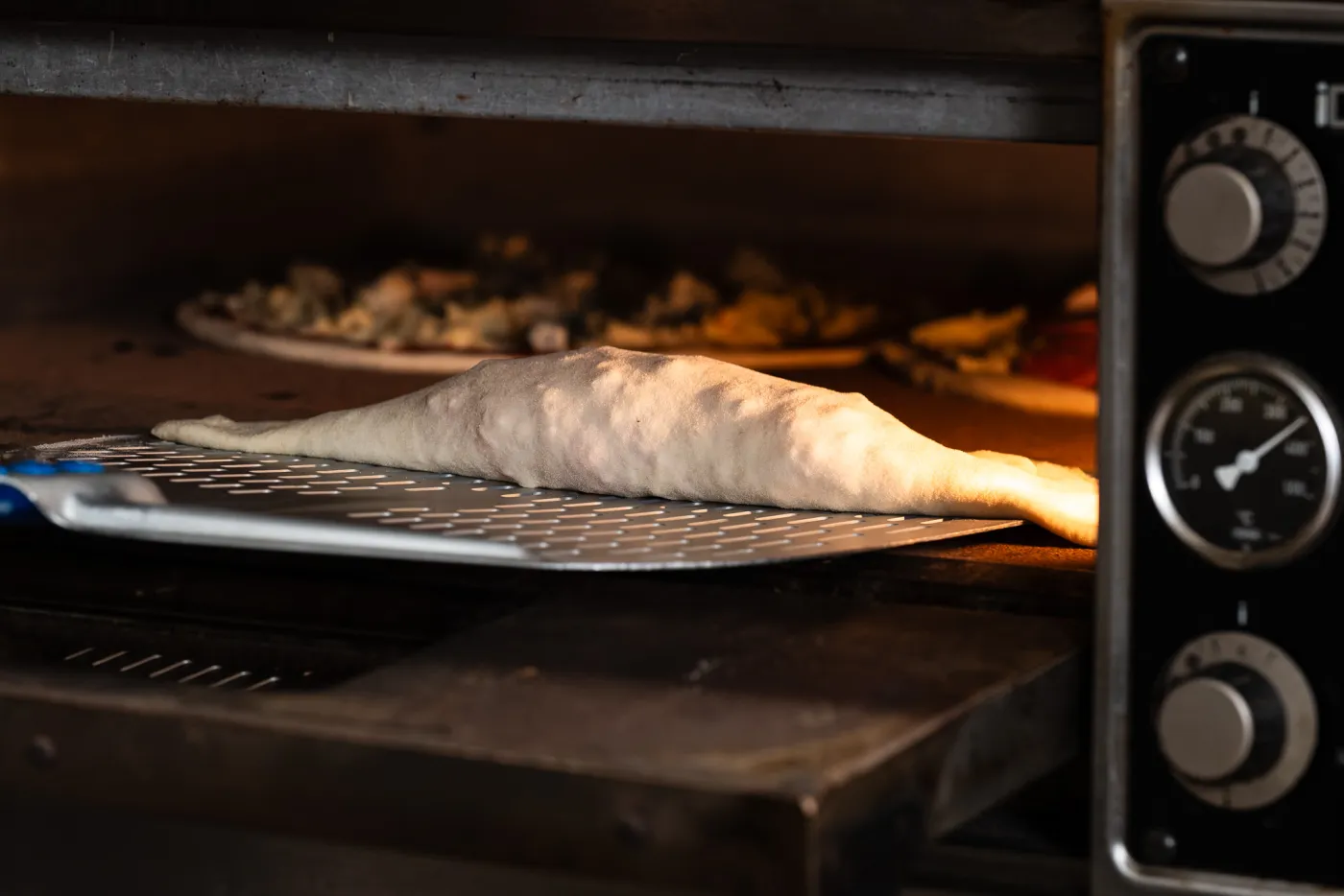A calzone being placed into the Pizza Calzone oven